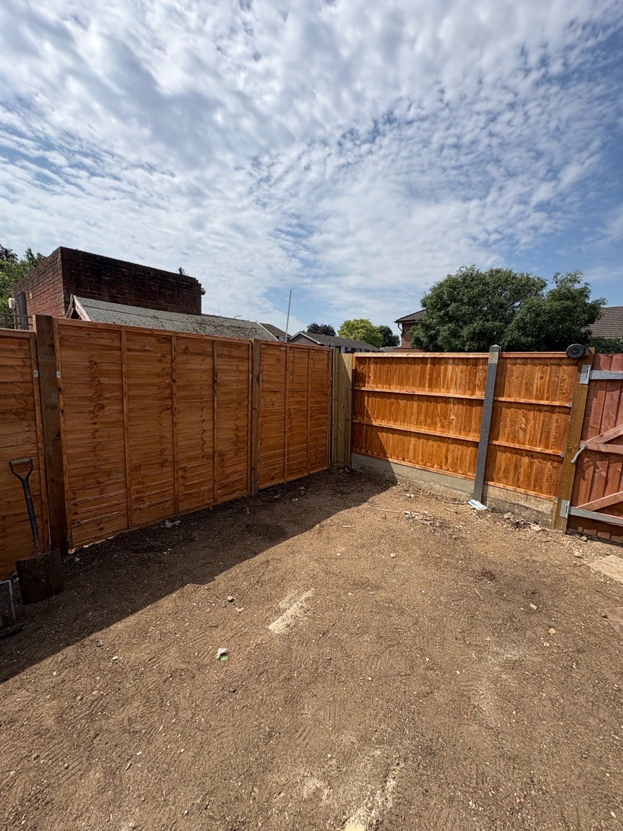 New timber lap fence panels with concrete posts along a cleared garden boundary